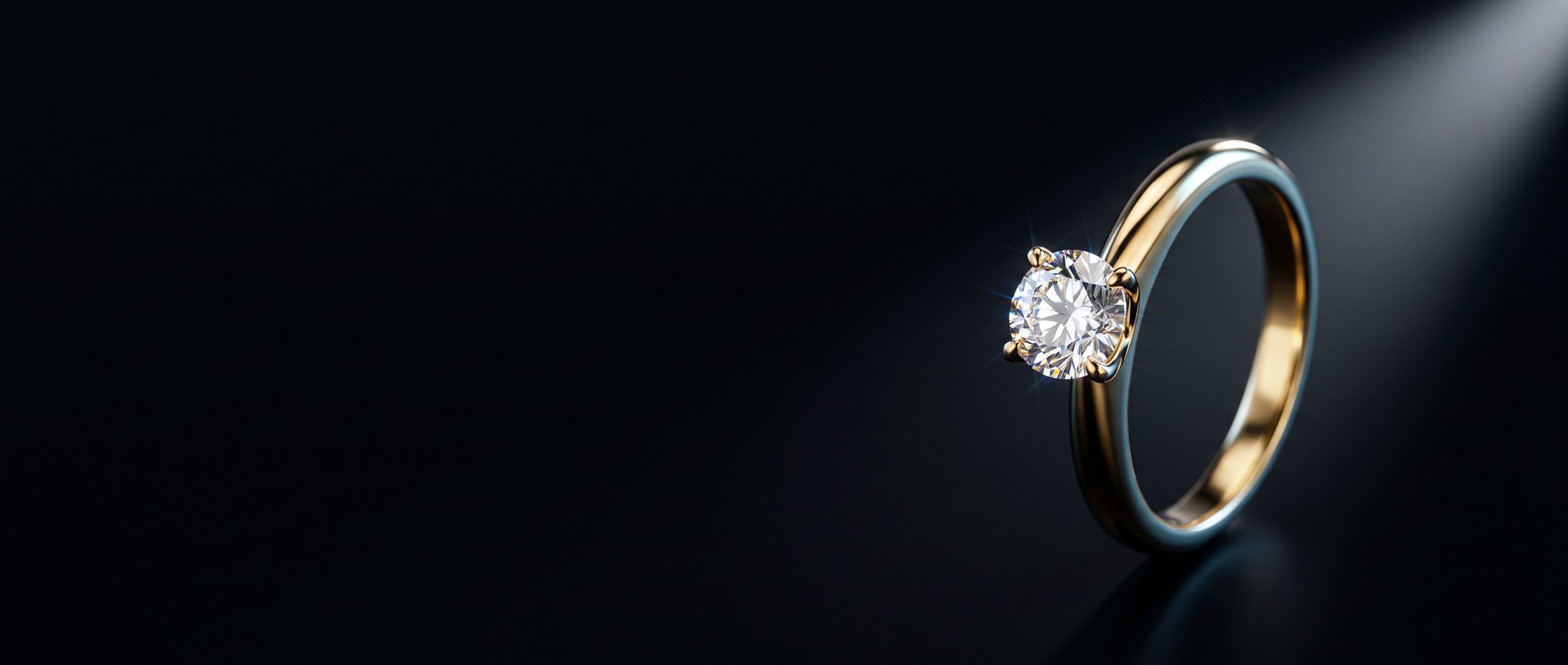 An 18k gold solitaire ring lit against a black background